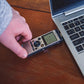 a person holding a cell phone next to a laptop